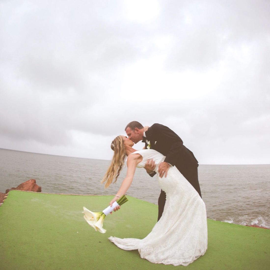 Newlyweds kissing by the sea