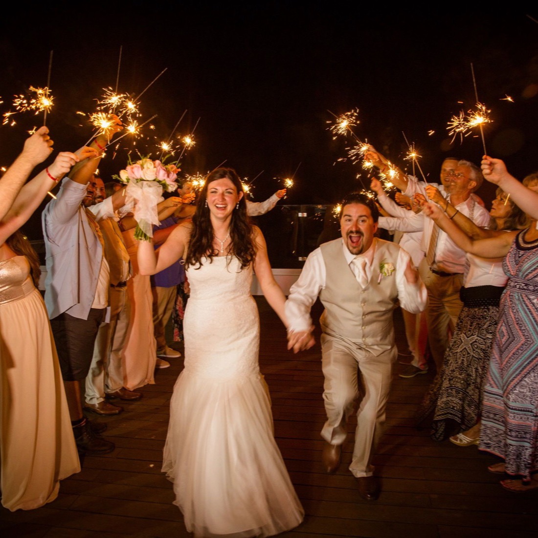 Newlyweds making their exit through a tunnel of sparklers held by their guests