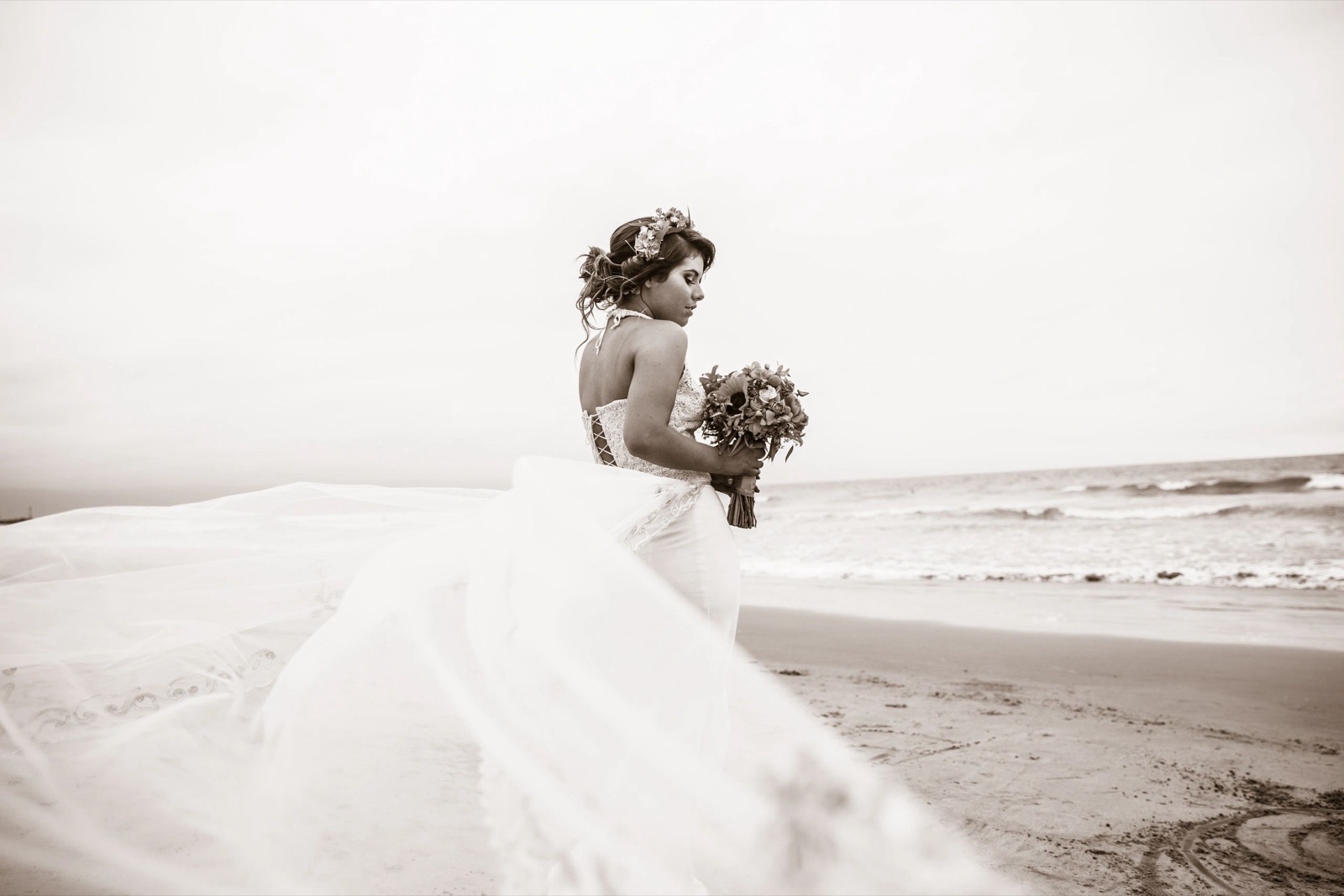 Bride on the beach with her veil in the wind, in black and white